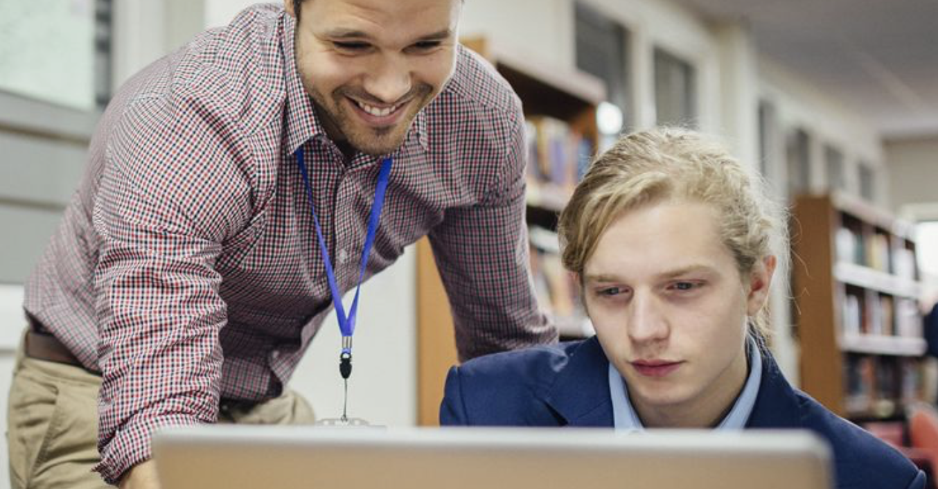 A teacher helps a school student with an online application